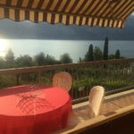 Balcone di Casa Angelo con tavolo e sedie, vista panoramica sul Lago di Garda al tramonto
