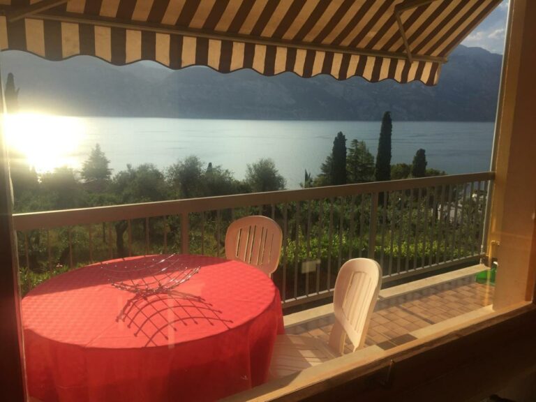 Balcone di Casa Angelo con tavolo e sedie, vista panoramica sul Lago di Garda al tramonto