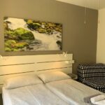 Camera matrimoniale con quadro cascata, poltrona e armadio