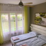 Camera con letto singolo, ventilatore a soffitto e tende verdi
