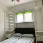 Camera matrimoniale con ventilatore colorato, scaffali e tende verdi