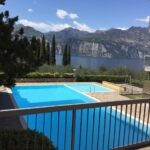 Piscina esterna con vista sul Lago di Garda, cipressi e montagne