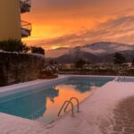Piscina del residence con neve e cielo arancione al tramonto