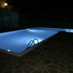 Piscina con illuminazione notturna, scaletta e pavimentazione in pietra