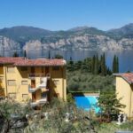 Vista panoramica del Residence La Perla con piscina, lago e montagne