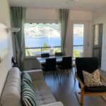 Soggiorno con divano e poltrona, vista lago dalle ampie finestre