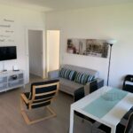 Soggiorno con divano, tavolo da pranzo, TV e scritta benvenuto